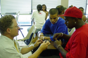 Gary Winn (left), WVU professor of industrial engineering, shows Jeremy Booker (far right), high school student from Charleston, how to build a small electric motor for under a dollar during last year\'s Engineers of Tomorrow summer program at WVU. T