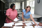 Lourdes Cottingham (left) and Megan Shope go over the materials one more time in preparation for Saturday’s (Aug. 26) “Sisters Committed to Better Health” outreach event in Morgantown. The health and wellness forum for black women is spo