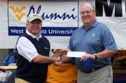 Steve Douglas, president and chief executive officer of the WVU Alumni Association, presents a $15,000 check to John Skinner of Charles Town during the WVU-Marshall game.  John hit a hole-in-one during the Association\'s Gold & Blue Weekend at St