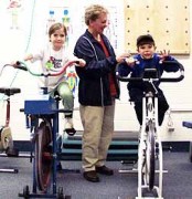  Linda Carson, the Ware Distinguished Professor in the WVU School of Physical Education, helps two Choosy Kids Club members get fit on stationary bikes. Carson, who has devoted her career to fighting childhood obesity, is among four recipients of the high