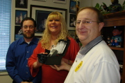 Bartlett House staff members (from left) Jason Walsh, resource manager, and Keri DeMasi, director, accept a preliminary breath tester (PBT) from Bob Roberts, WVU Public Safety chief, Jan. 19 at the Prete Building. 