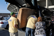 Volunteers help a shopper load a couch into her car at the Blue and Gold Mine Sale, held at Milan Puskar Stadium.