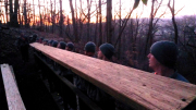 ROTC Cadets preparing to drop bridge beam into position from deck of existing bridge.